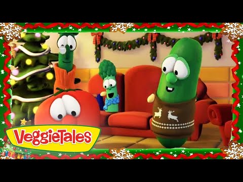 VeggieTales characters—tomato, cucumber in a brown Christmas sweater, and broccoli—sitting in a festively decorated living room with a Christmas tree.