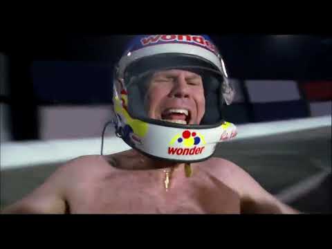 Official trailer frame — Ricky Bobby in fire suit with pit lane chaos behind him