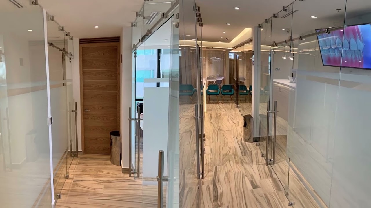 Interior of La Clínica Dental in Mexico City, featuring glass partitions, modern decor, and waiting area with teal chairs, emphasizing a welcoming and aesthetic orthodontic environment.