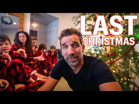 Focused man in a black shirt sits in front of a decorated Christmas tree, with children in red plaid pajamas behind him; bold 'LAST CHRISTMAS' text overlays the scene.