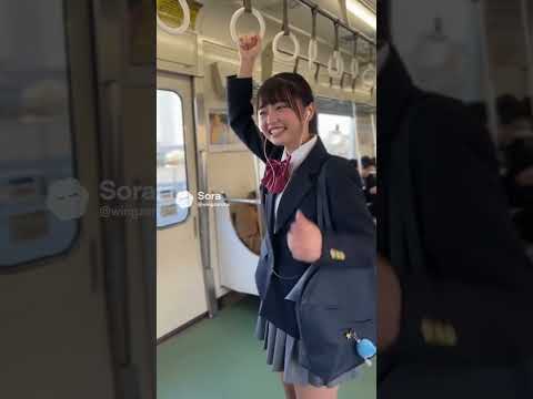 電車の中でつり革を持って遊びながら楽しそうにしている女子高生