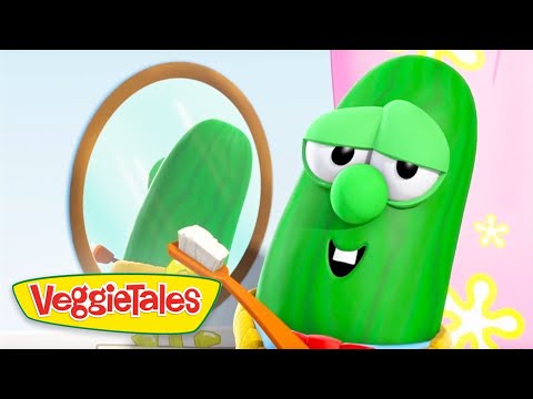 A green VeggieTales cucumber character smiles while brushing teeth with an orange toothbrush in front of a round mirror in a bright scene.