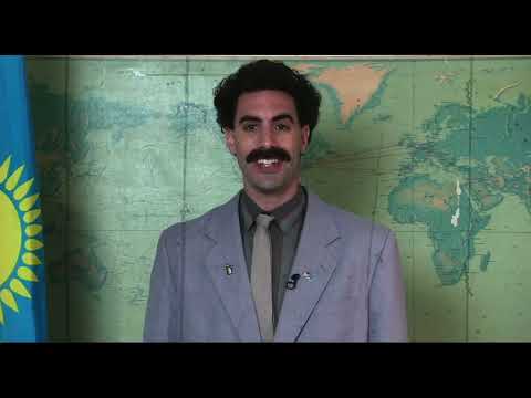 Trailer still: Borat driving through the U.S. heartland with a grin and a thumbs-up