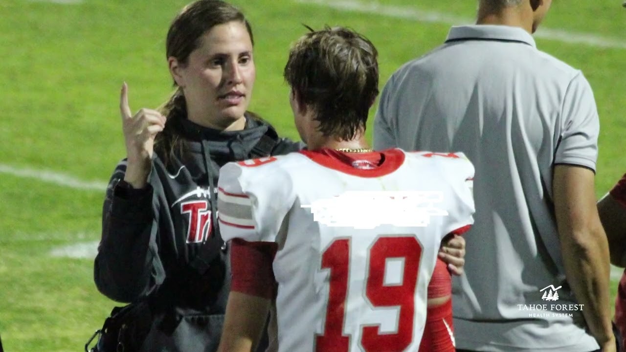 Coach speaking with a young male football player on a football field
