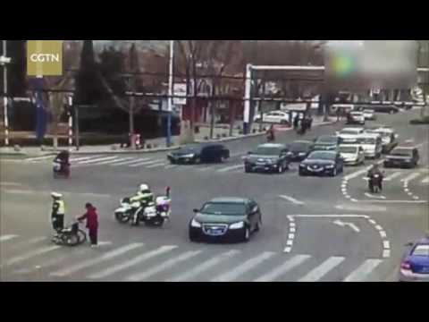 Two police officers escort a senior citizen across road