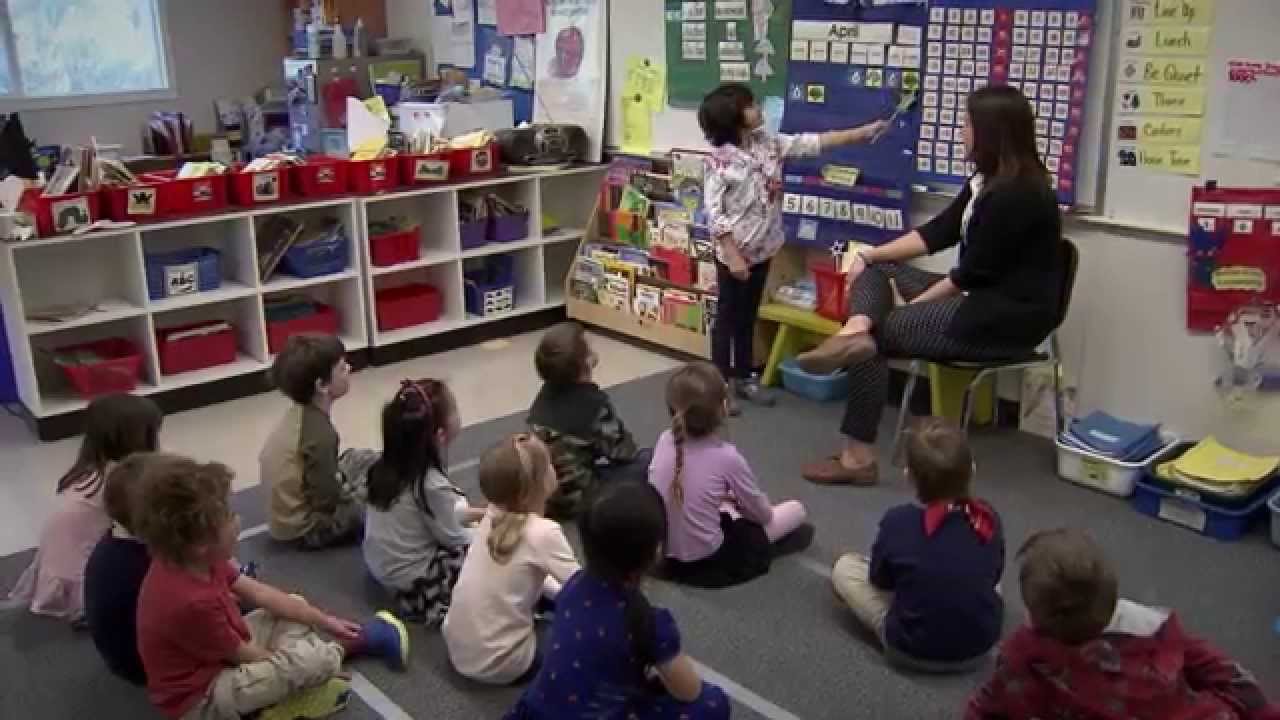 Fernanda at the front of her class using the pointer to point to items in the pocket chart