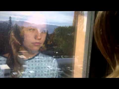 Alaina in a hospital gown looking out the window