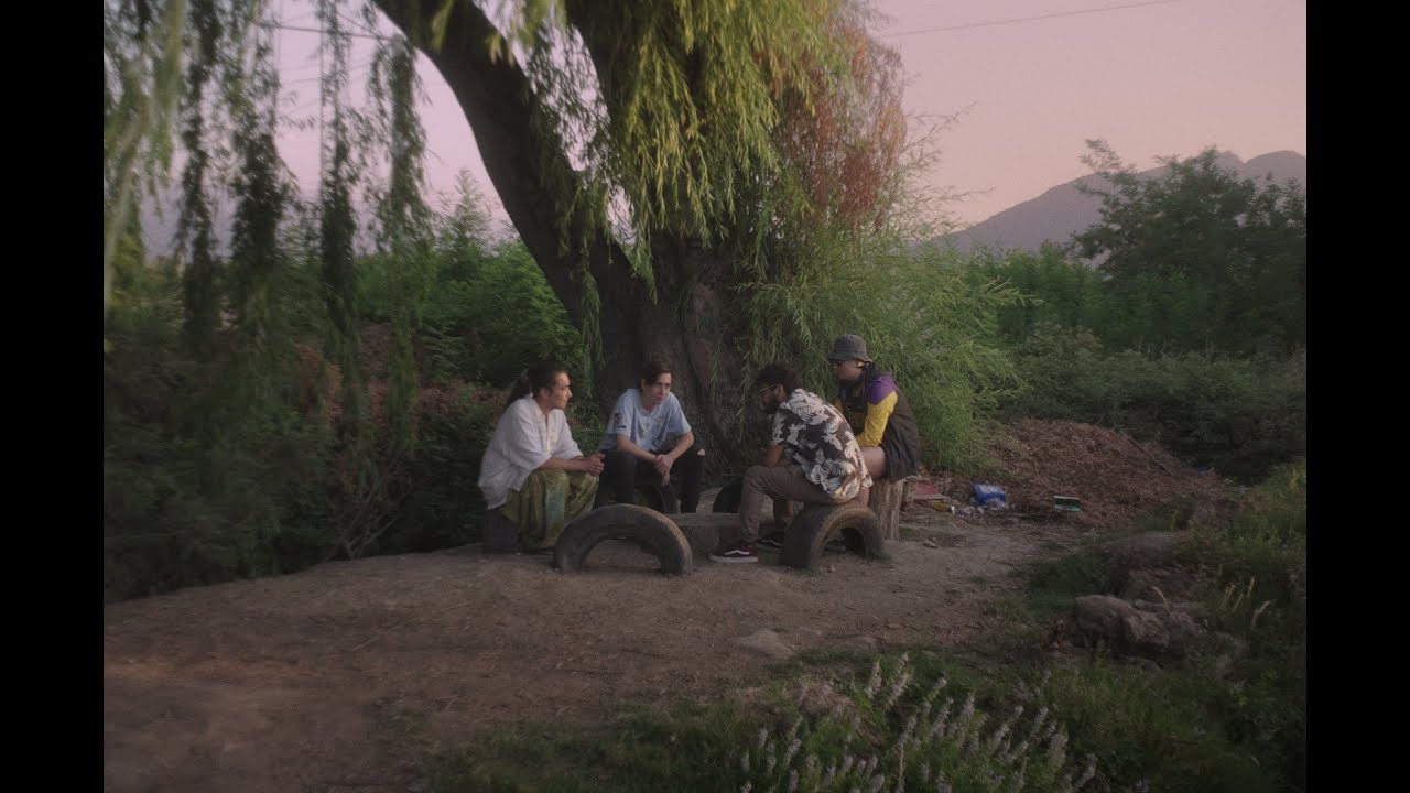 A group of young women are sitting down together in a wooded area