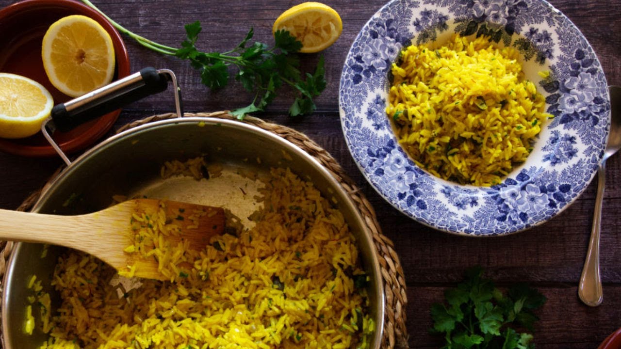 A large pot of Mediterranean yellow rice is served into decorative bowls