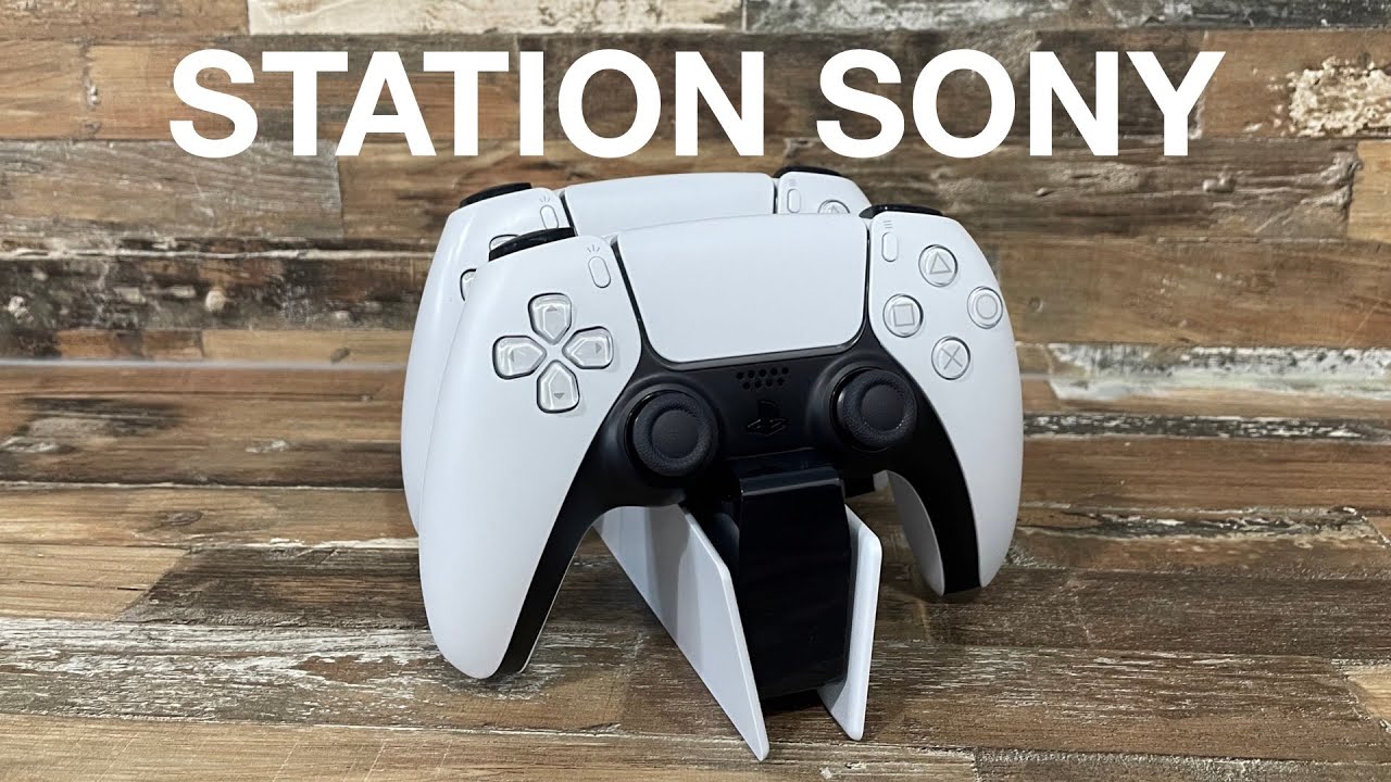Vue d'ensemble de la station de rechargement officielle Sony DualSense, posée sur un meuble TV avec une manette PS5 en charge.