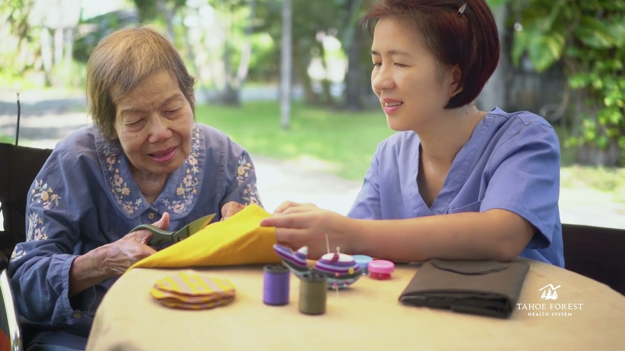 Therapist assisting an older woman with a craft