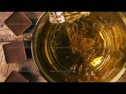 Slow motion pour into a glass of Bourbon near the chocolate top view