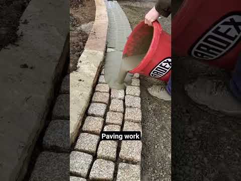 Pavement construction - worker laying granite stone pavers & pouring grout