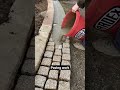 Pavement construction - worker laying granite stone pavers & pouring grout