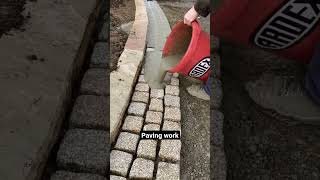 Pavement construction - worker laying granite stone pavers & pouring grout