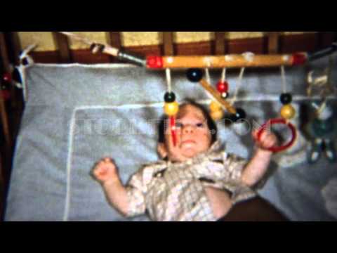 1958: Baby plays wooden mobile rings above crib bed. MOLINE, ILLINOIS