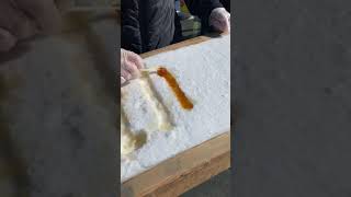 Download lagu Person shows a Canadian delicacy of maple syrup poured into snow and rolled on a stick! mp3