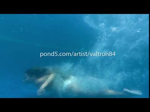 Active young woman dives into spectacular empty pool and splashes glassy water. Caucasian girl jumps