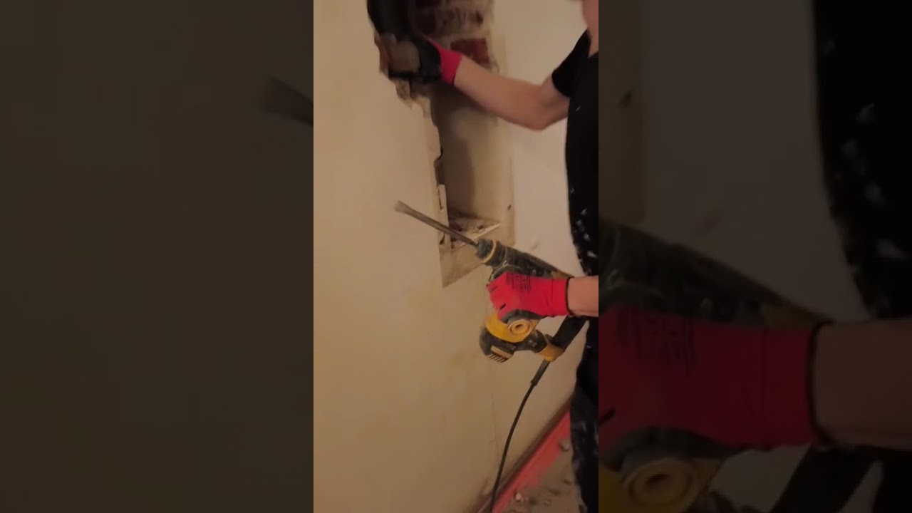 Pracownik wykonuje kucie w ścianie podczas remontu łazienki na Bielanach