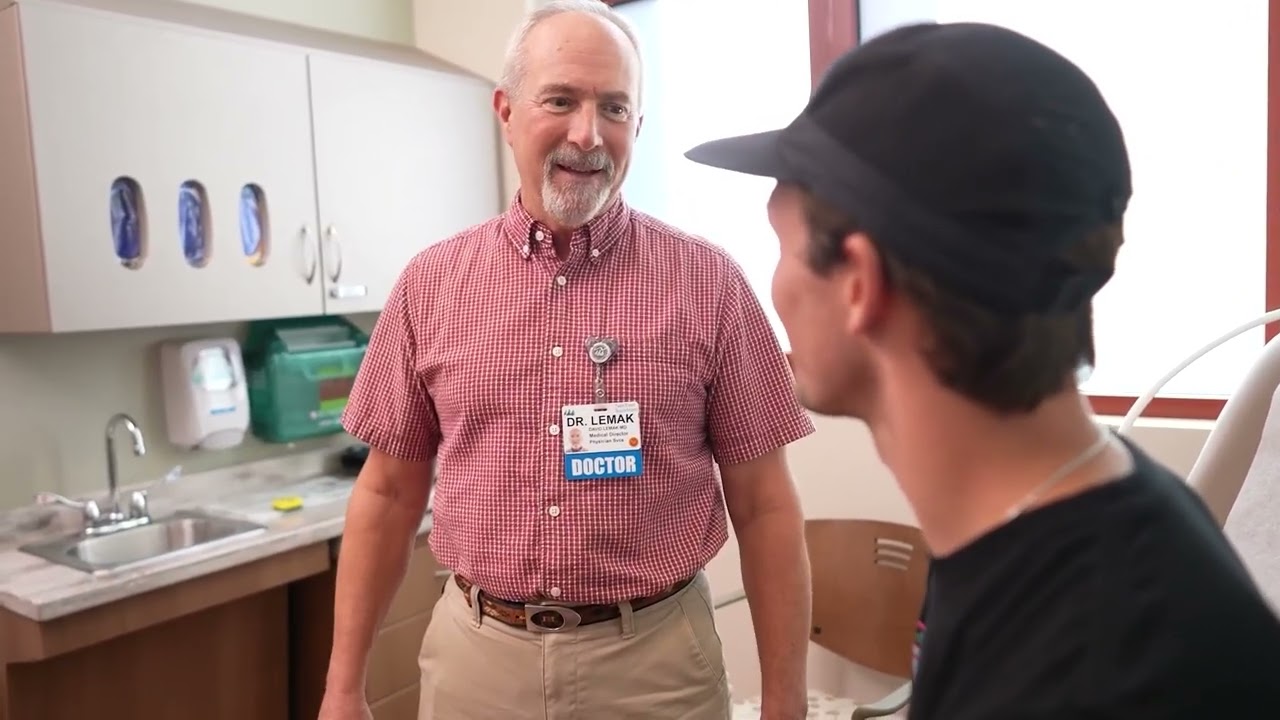 Dr. David Lemak, Medical Director of Urgent Care, speaking with a young man in a patient exam room