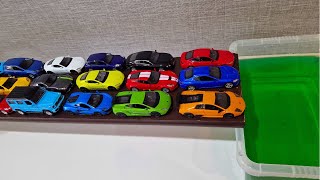 Colourful mini cars sliding down and falling into green water