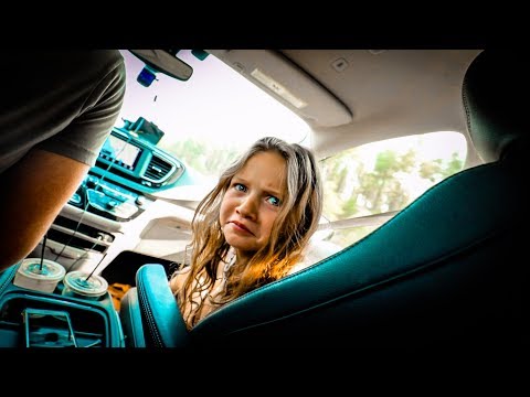 Young girl in a car looking worried, with the dashboard and two drink cups visible nearby.