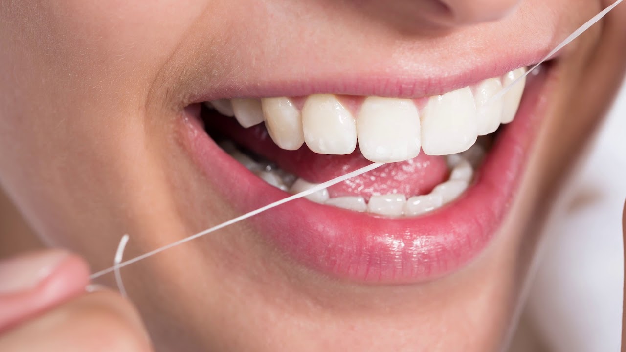 Close up of person flossing their teeth