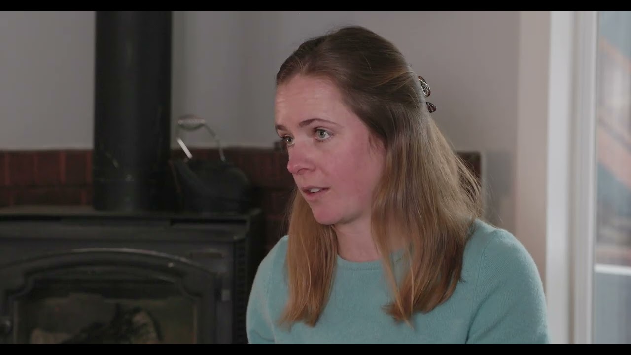Professional big mountain and freeride skier Kelsey Wittels sitting in her living room in front of a wood-burning stove