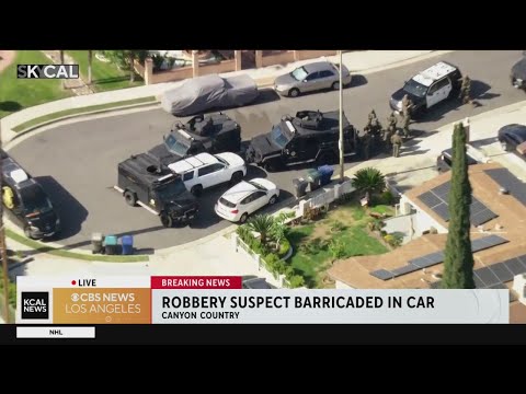 Armed robbery suspect barricaded inside car