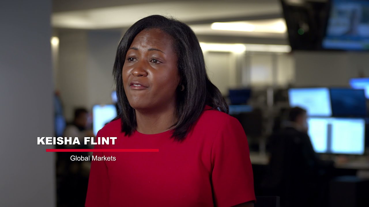 Professional woman in a red dress speaking about Global Markets in a modern office setting, emphasizing the importance of video marketing for law firms.