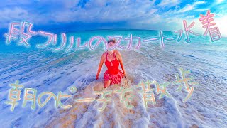 朝のビーチを段フリルのスカート水着で…。