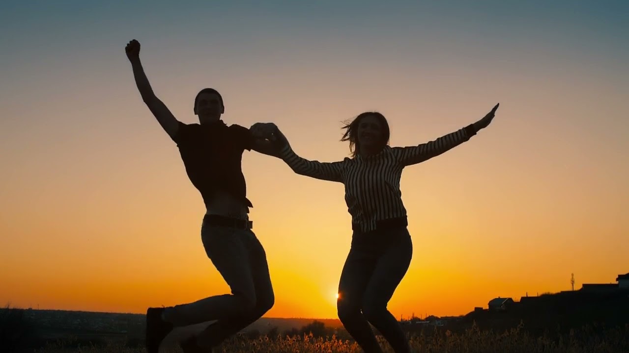 silhouette of a couple jumping in the sunset