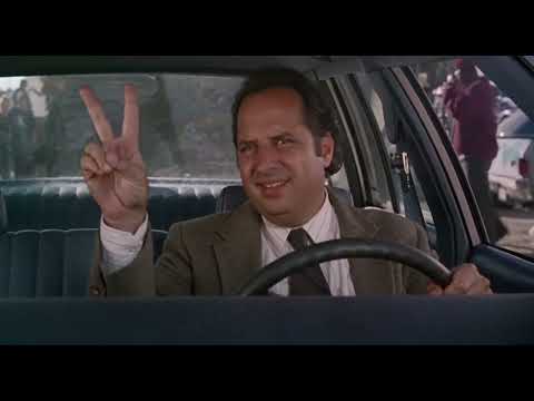 Trailer frame of faculty lounge and hall monitors—setups where ironic pop needle-drops land