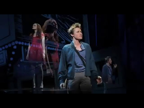 Stage photo style frame from Spider-Man Turn Off the Dark trailer with Spider-Man over the audience