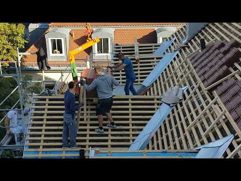 Albanische Dachdecker verteilen Dachziegel auf Biberschwanzdach