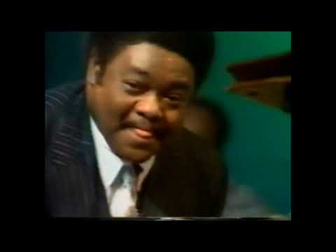 Fats Domino pushing grand piano across the stage