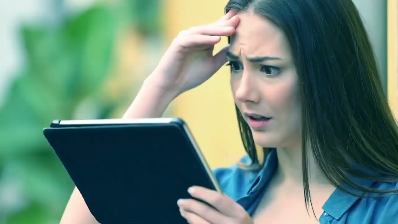 Een vrouw kijkt zorgelijk naar haar tablet.