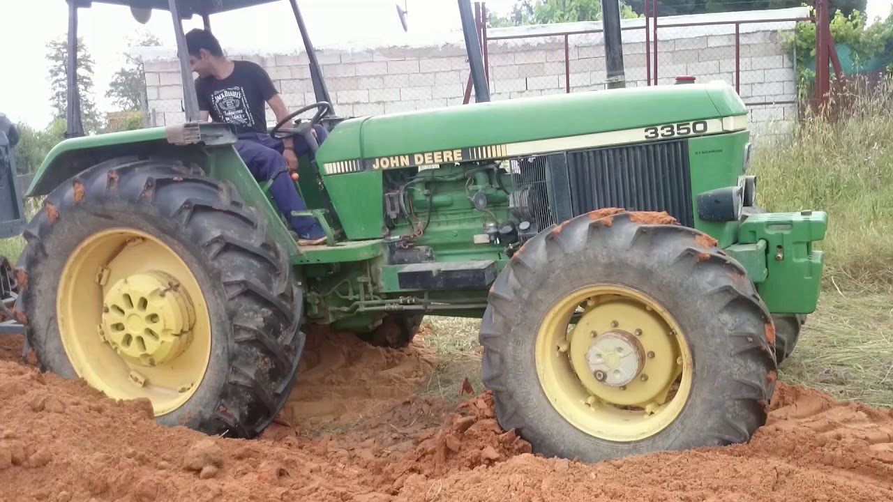 John Deere abriéndose paso entre los montones de tierra con remolque