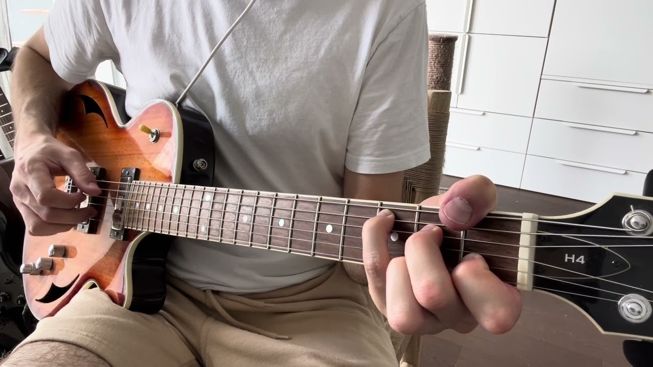 Close-up of a right hand fingerpicking a guitar, thumb on the low E bass string, middle and ring fingers on the upper strings.