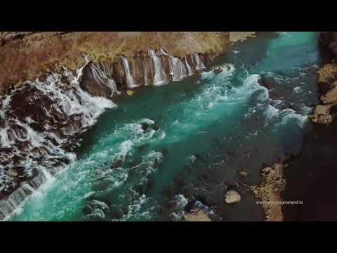 Aerial photograph of the Hraunfossar waterfalls, where turquoise water cascades over black lava rock in West Iceland.