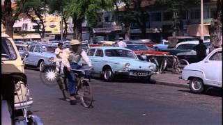 Vehicles move down a street and girls cross a road in Saigon, Vietnam. HD Stock Footage