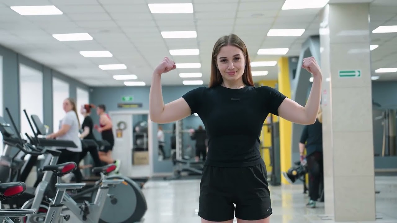 Young woman flexing her arms in a gym