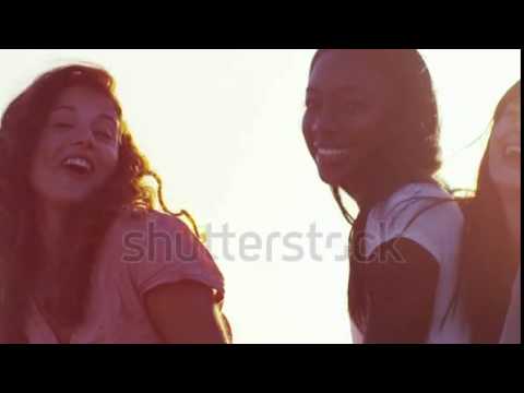 Happy carefree young female friends dancing on the beach. In slow motion