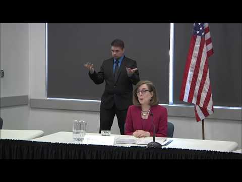 Governor Kate Brown presenting at the May 7th press conference with a sign language interpretor in the background