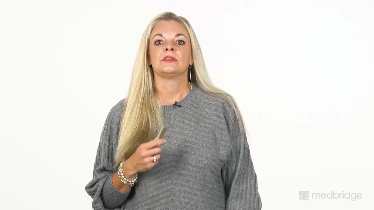 A woman with long blonde hair in a gray sweater stands holding a small object, symbolizing digital healthcare at medbridge.