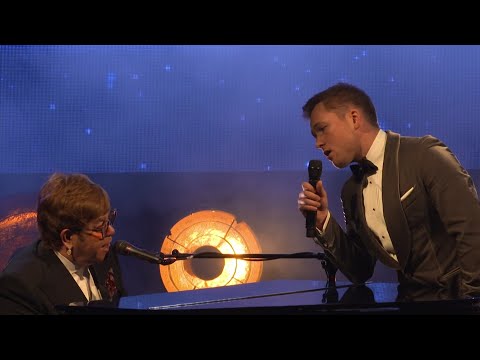 Elton John and Bernie Taupin reflect on how emotional they felt watching biopic "Rocketman," as Elton and the film's star - Taron Egerton - duet on the title track. (May 17)