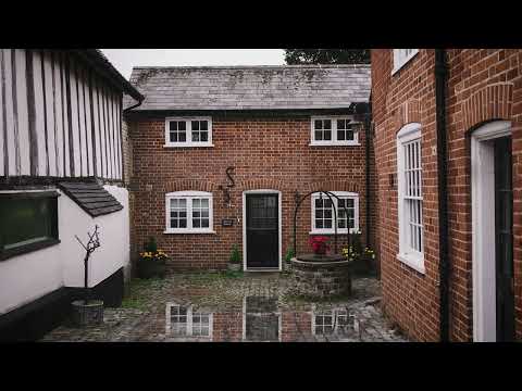 Rain on a cobblestone courtyard outside a charming small cottage in Hadleigh, Suffolk, UK