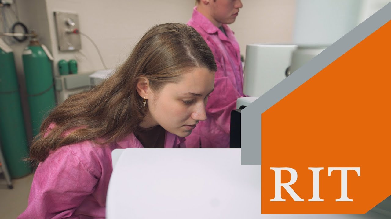 Woman stands in front of a piece of equipment. An orange overlay has a white RIT logo on it.