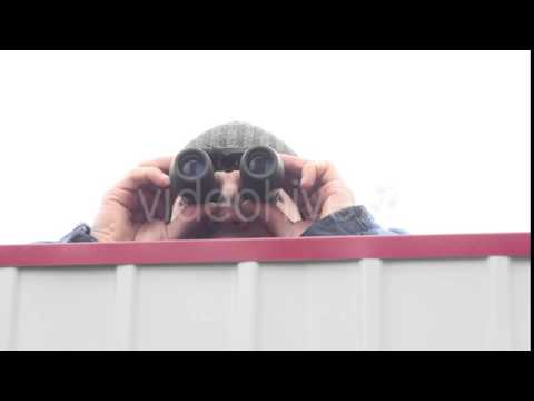 Man With Binoculars Jumping Over the Fence and Looking Around
