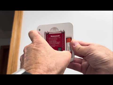 Part of a video titled How to Change Batteries in a Honeywell Thermostat - YouTube